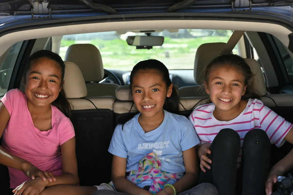 Niñas sonriendo en el asiento trasero del coche